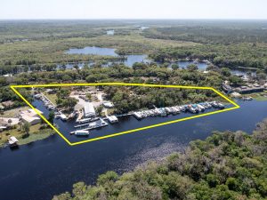 Drone shot of several boats parked on the St John's River near forested land.
